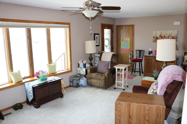 carpeted living area featuring ceiling fan and baseboards