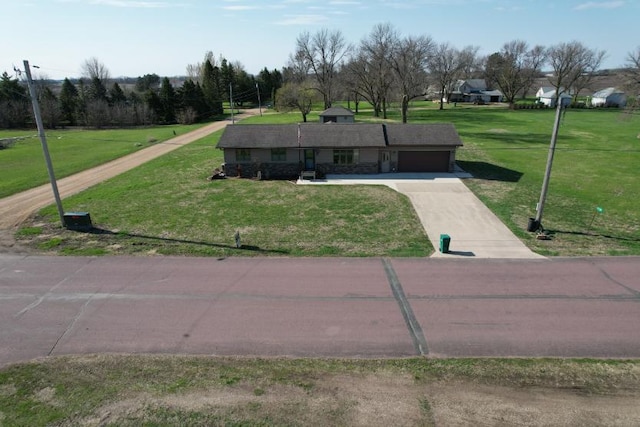 view of property's community featuring a garage, concrete driveway, and a yard