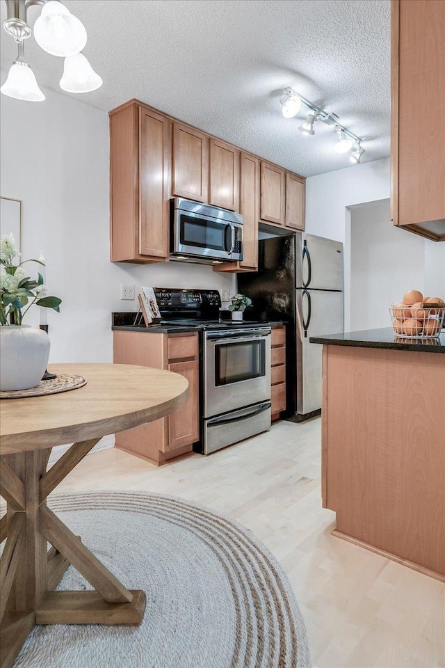 821 Douglas Ave Unit 105, Minneapolis, MN 55403 - kitchen featuring stainless steel appliances, rail lighting, a textured ceiling, pendant lighting, and dark countertops
