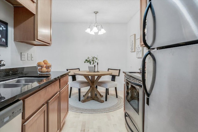 821 Douglas Ave Unit 105, Minneapolis, MN 55403 - kitchen featuring a sink, a chandelier, dark stone countertops, light wood-style floors, and stainless steel appliances