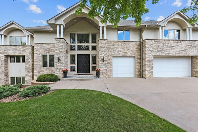 view of front facade with stucco siding, a front yard, stone siding, an attached garage, and driveway