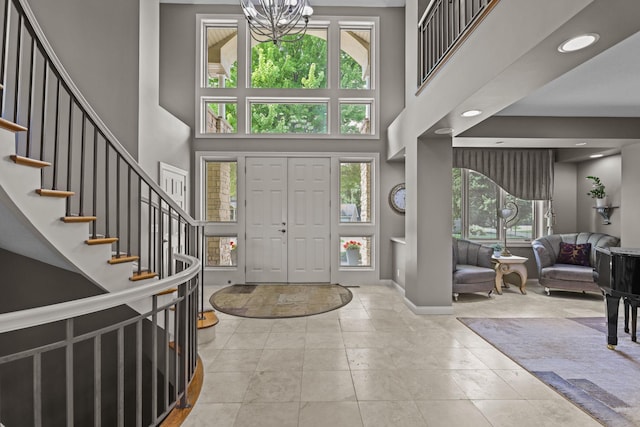 foyer entrance featuring baseboards, stairs, a high ceiling, and an inviting chandelier