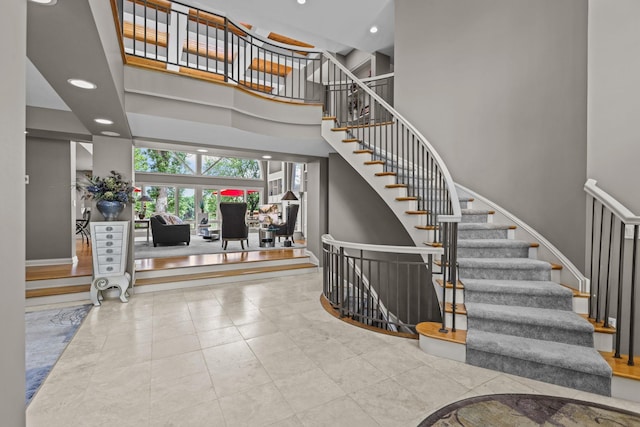 staircase featuring a towering ceiling and recessed lighting