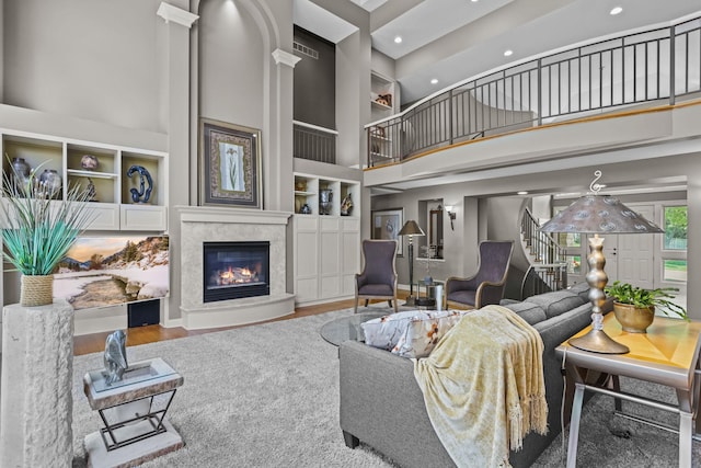 living area with built in features, a fireplace, recessed lighting, a towering ceiling, and stairs