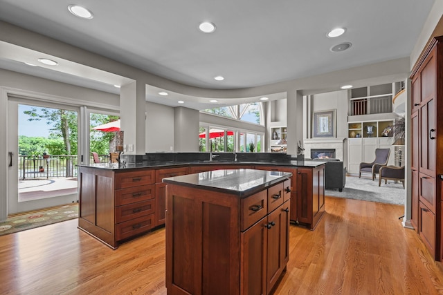 kitchen featuring a peninsula, a center island, a glass covered fireplace, and plenty of natural light