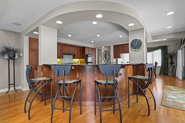 kitchen featuring a peninsula, light wood finished floors, recessed lighting, and a kitchen breakfast bar