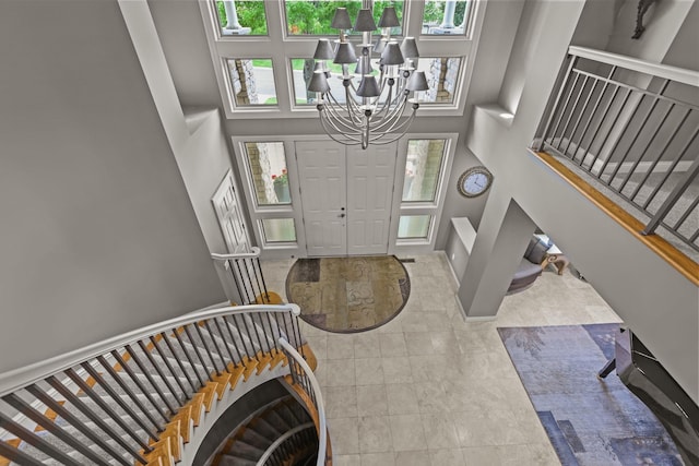 foyer featuring a wealth of natural light, a high ceiling, a notable chandelier, and stairs