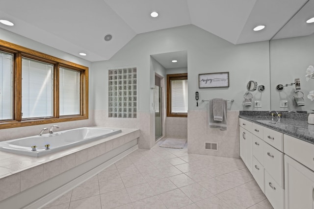 bathroom with a stall shower, tile patterned flooring, a wainscoted wall, visible vents, and tile walls