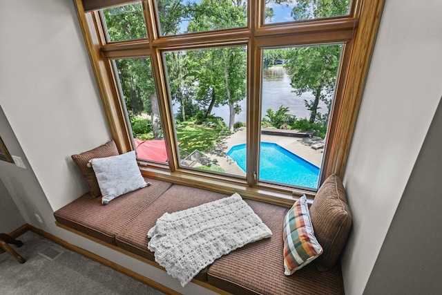 interior space with a water view, plenty of natural light, carpet flooring, and visible vents