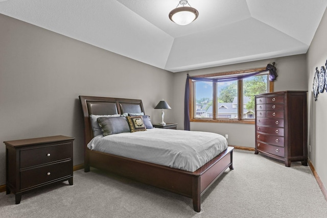 carpeted bedroom featuring baseboards and vaulted ceiling
