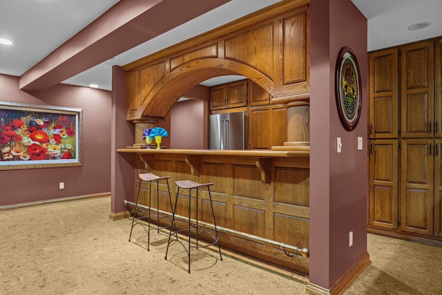bar featuring high end refrigerator, baseboards, a bar, and recessed lighting