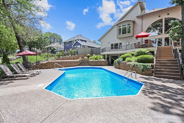 view of pool featuring a wooden deck, a patio area, fence, stairs, and a fenced in pool