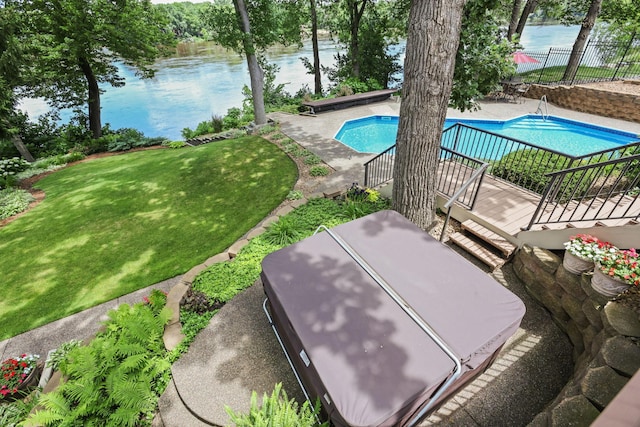 exterior space featuring a fenced in pool, a patio area, a water view, fence, and a lawn