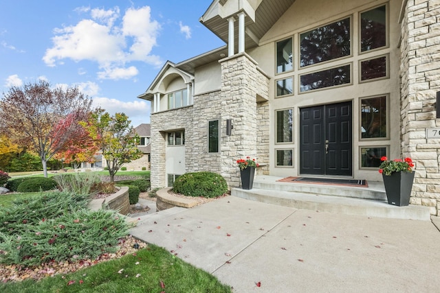 view of exterior entry featuring stucco siding and stone siding
