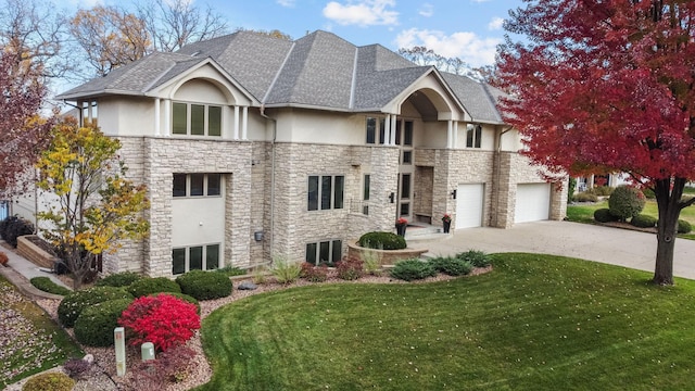 view of front facade with stucco siding, roof with shingles, stone siding, a front lawn, and concrete driveway