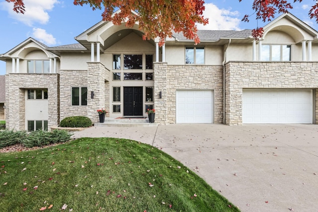 view of front of home with a front yard, driveway, stucco siding, and stone siding