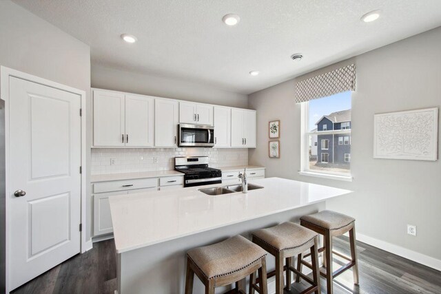 17030 Draper Way, Lakeville, MN 55044 - kitchen with appliances with stainless steel finishes, a sink, decorative backsplash, dark wood-style floors, and a breakfast bar