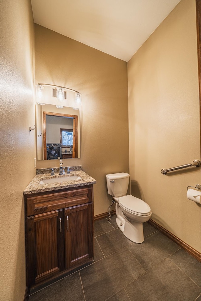 46174 County Highway 35, Vergas, MN 56587 - bathroom with toilet, vanity, baseboards, vaulted ceiling, and tile patterned floors