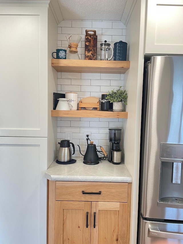 1211 Diagonal Rd, Worthington, MN 56187 - kitchen view of stainless steel fridge, open shelves, light countertops, decorative backsplash, and a textured ceiling