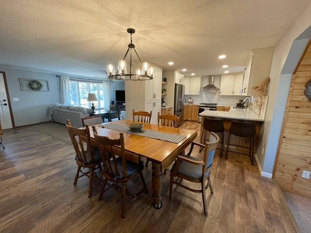 1211 Diagonal Rd, Worthington, MN 56187 - dining room featuring dark wood-type flooring, a chandelier, a textured ceiling, recessed lighting, and baseboards