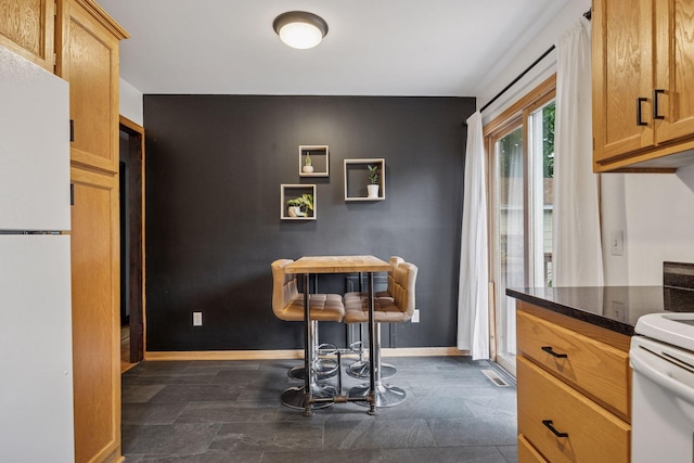 3011 Brunswick Ave S, Saint Louis Park, MN 55416 - kitchen featuring freestanding refrigerator, baseboards, and dark stone counters
