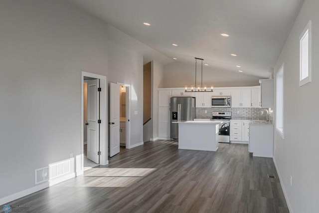 kitchen with a sink, dark wood finished floors, white cabinetry, stainless steel appliances, and a kitchen island
