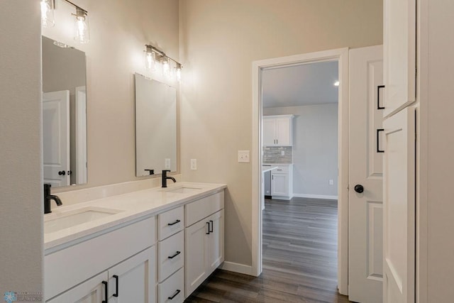 bathroom with wood finished floors, double vanity, a sink, and baseboards