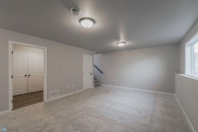 below grade area with carpet floors, baseboards, visible vents, and stairs