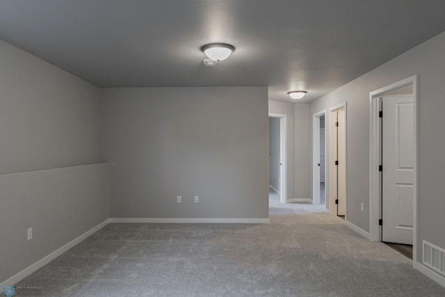 carpeted empty room featuring baseboards and visible vents