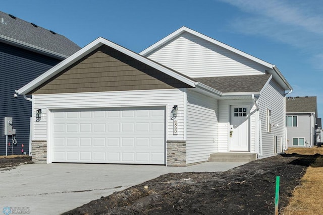 view of front of home featuring an attached garage, driveway, and stone siding