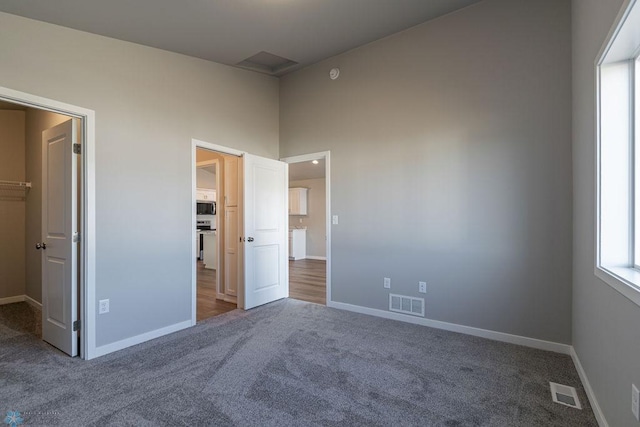 unfurnished bedroom featuring visible vents, baseboards, and carpet floors