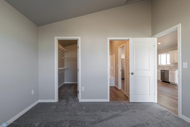 unfurnished bedroom featuring baseboards, lofted ceiling, and carpet