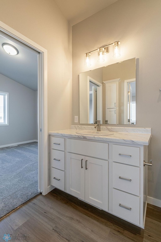 bathroom with baseboards, vaulted ceiling, vanity, and wood finished floors