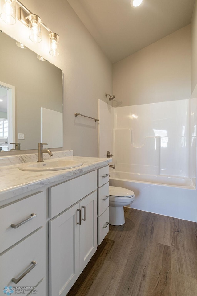 bathroom with toilet, vanity, tub / shower combination, and wood finished floors