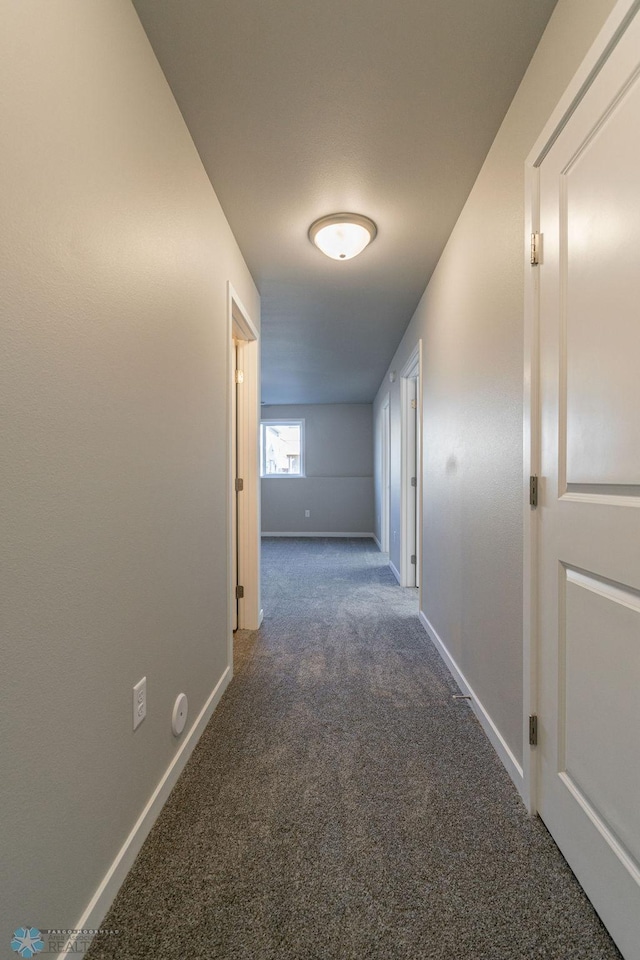 corridor with baseboards and carpet