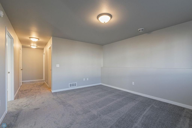 carpeted spare room with visible vents and baseboards