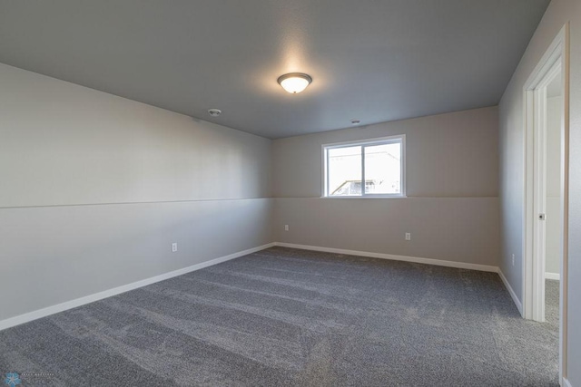 spare room featuring dark carpet and baseboards
