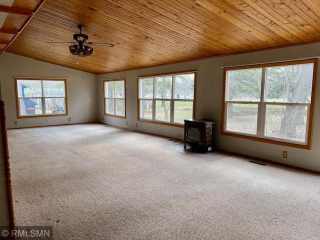 spare room with a wood stove, a ceiling fan, a healthy amount of sunlight, and wood ceiling