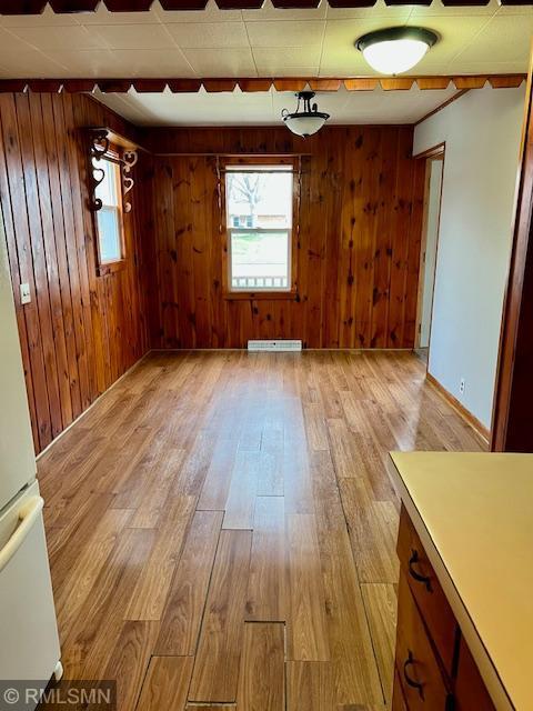 spare room with wood finished floors, wood walls, visible vents, and a healthy amount of sunlight