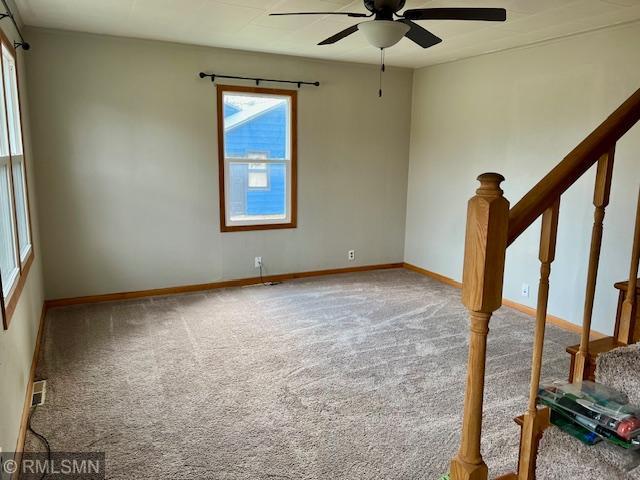 unfurnished room with stairway, carpet floors, baseboards, and ceiling fan