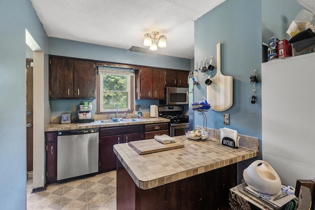 7716 Orchard Ave N, Brooklyn Park, MN 55443 - kitchen with stainless steel appliances, a sink, dark brown cabinets, and tile counters