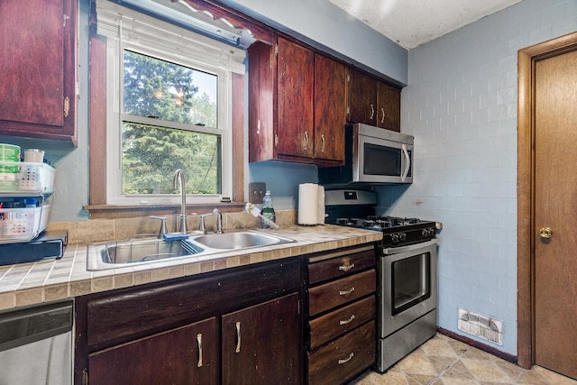 7716 Orchard Ave N, Brooklyn Park, MN 55443 - kitchen with stainless steel appliances, a sink, tile countertops, and dark brown cabinetry