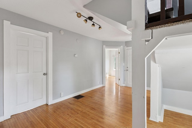 1208 University Ave NE, Minneapolis, MN 55413 - empty room with light wood finished floors, baseboards, a smoke detector, and rail lighting