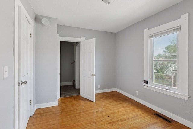 1208 University Ave NE, Minneapolis, MN 55413 - unfurnished bedroom featuring multiple windows, light wood-type flooring, and baseboards