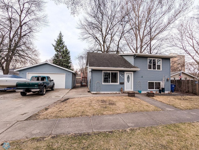 split level home with fence, an outbuilding, a detached garage, and a front yard