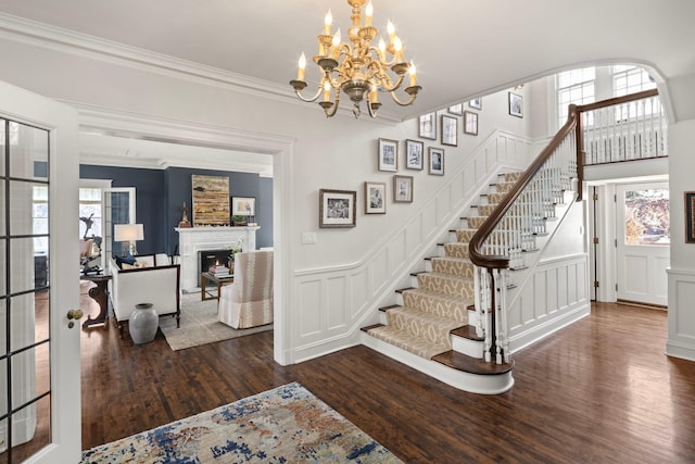 2774 Lake Of The Isles Pkwy, Minneapolis, MN 55416 - entrance foyer featuring stairway, wood finished floors, a lit fireplace, a decorative wall, and a chandelier