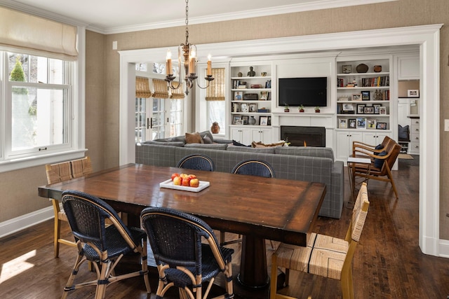2774 Lake Of The Isles Pkwy, Minneapolis, MN 55416 - dining room featuring dark wood-type flooring, a chandelier, a warm lit fireplace, and crown molding
