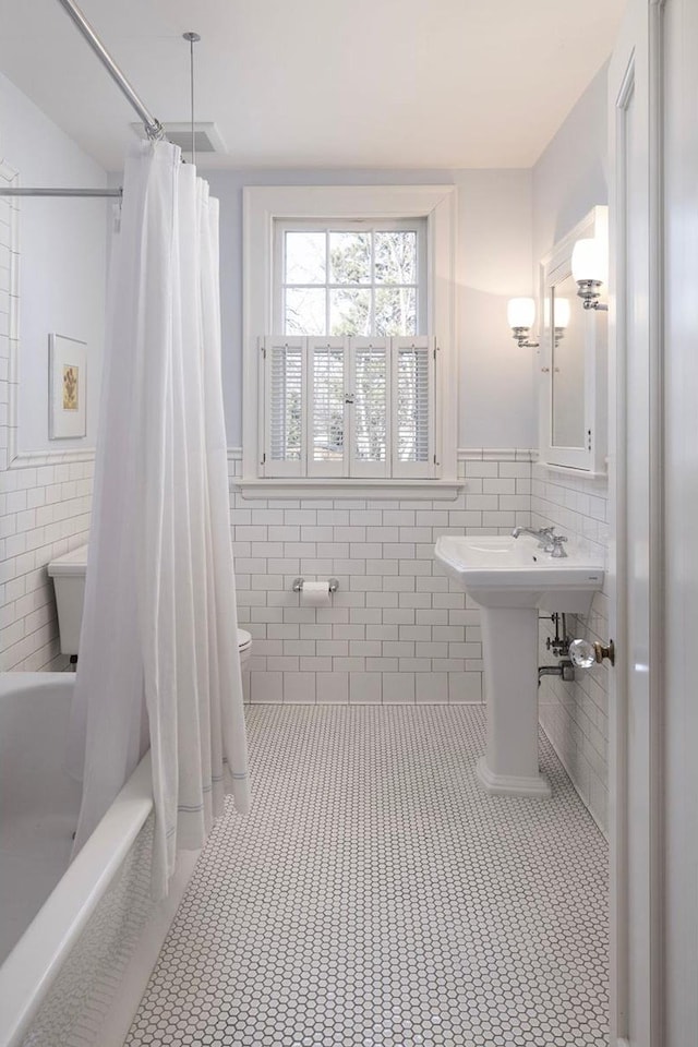 2774 Lake Of The Isles Pkwy, Minneapolis, MN 55416 - bathroom featuring tile walls, wainscoting, tile patterned floors, and shower / bath combo