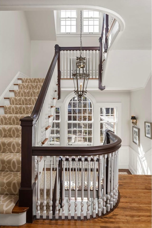 2774 Lake Of The Isles Pkwy, Minneapolis, MN 55416 - stairway featuring wood finished floors, a wainscoted wall, a chandelier, a decorative wall, and a towering ceiling