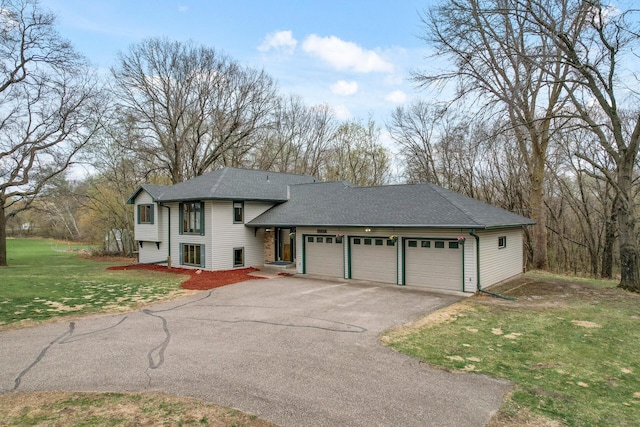 view of front facade with a front yard, driveway, a garage, and roof with shingles